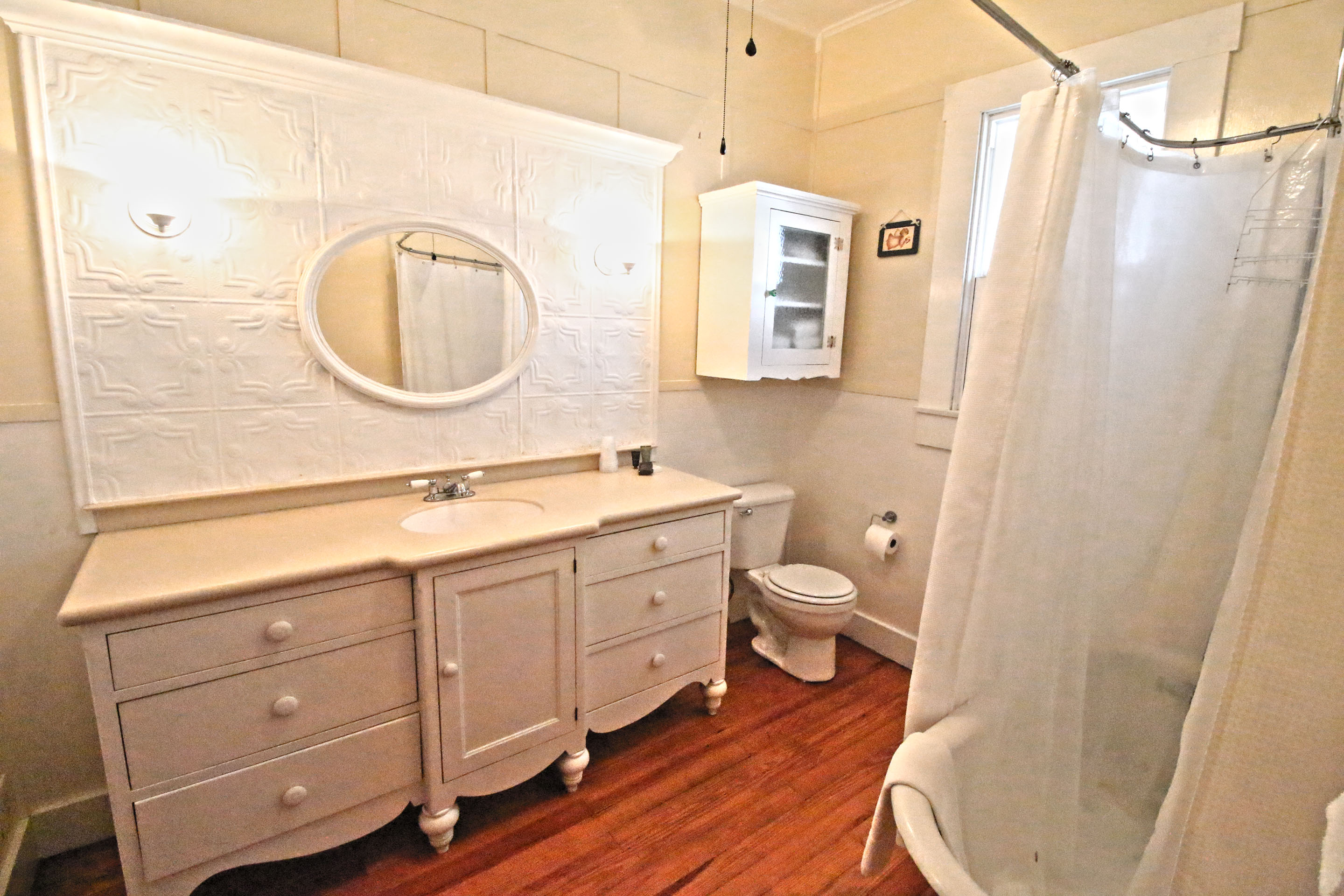 A white bathroom with a vanity, toilet, and shower