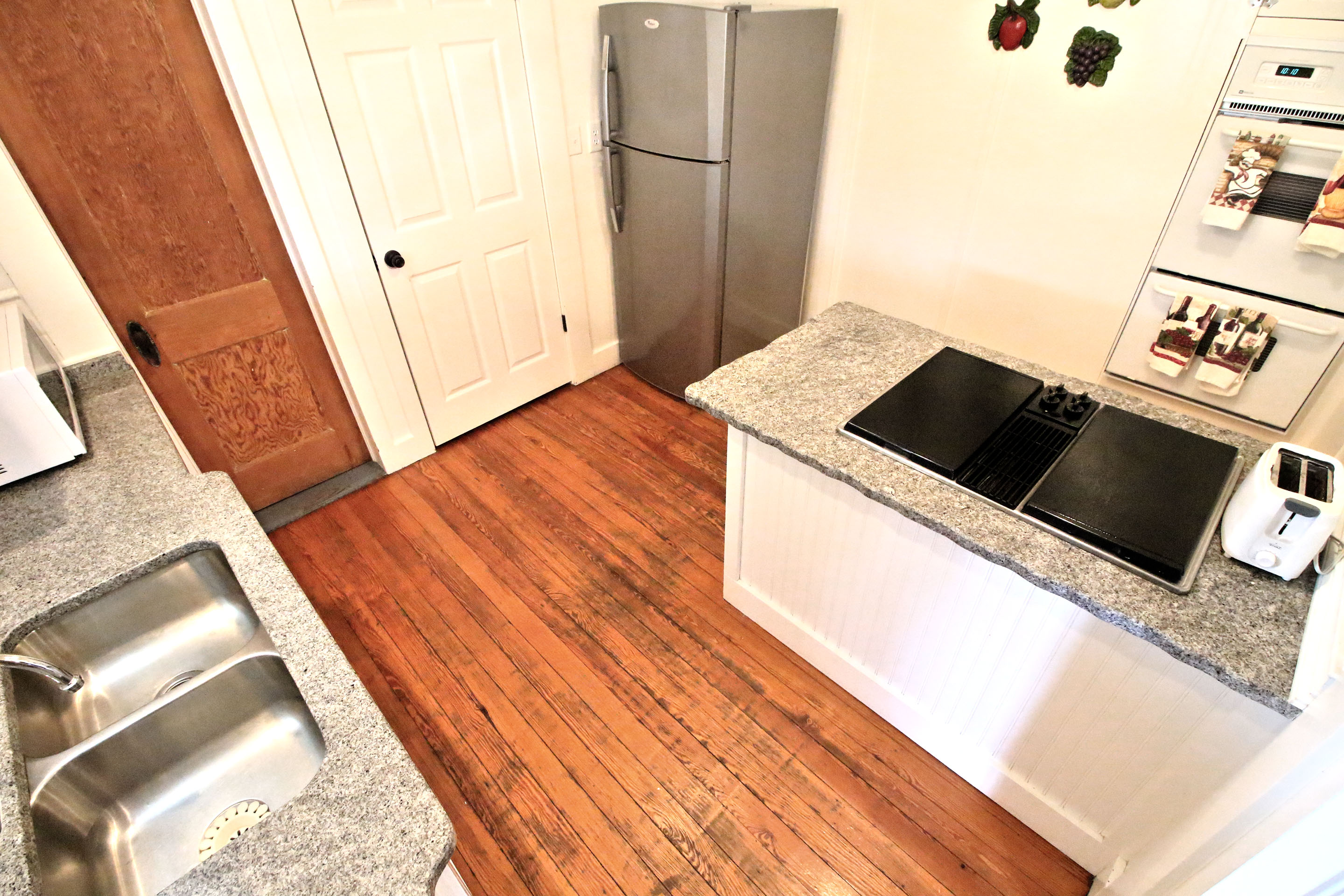 A kitchenette with stainless steel appliances, granite countertops, and a sink.