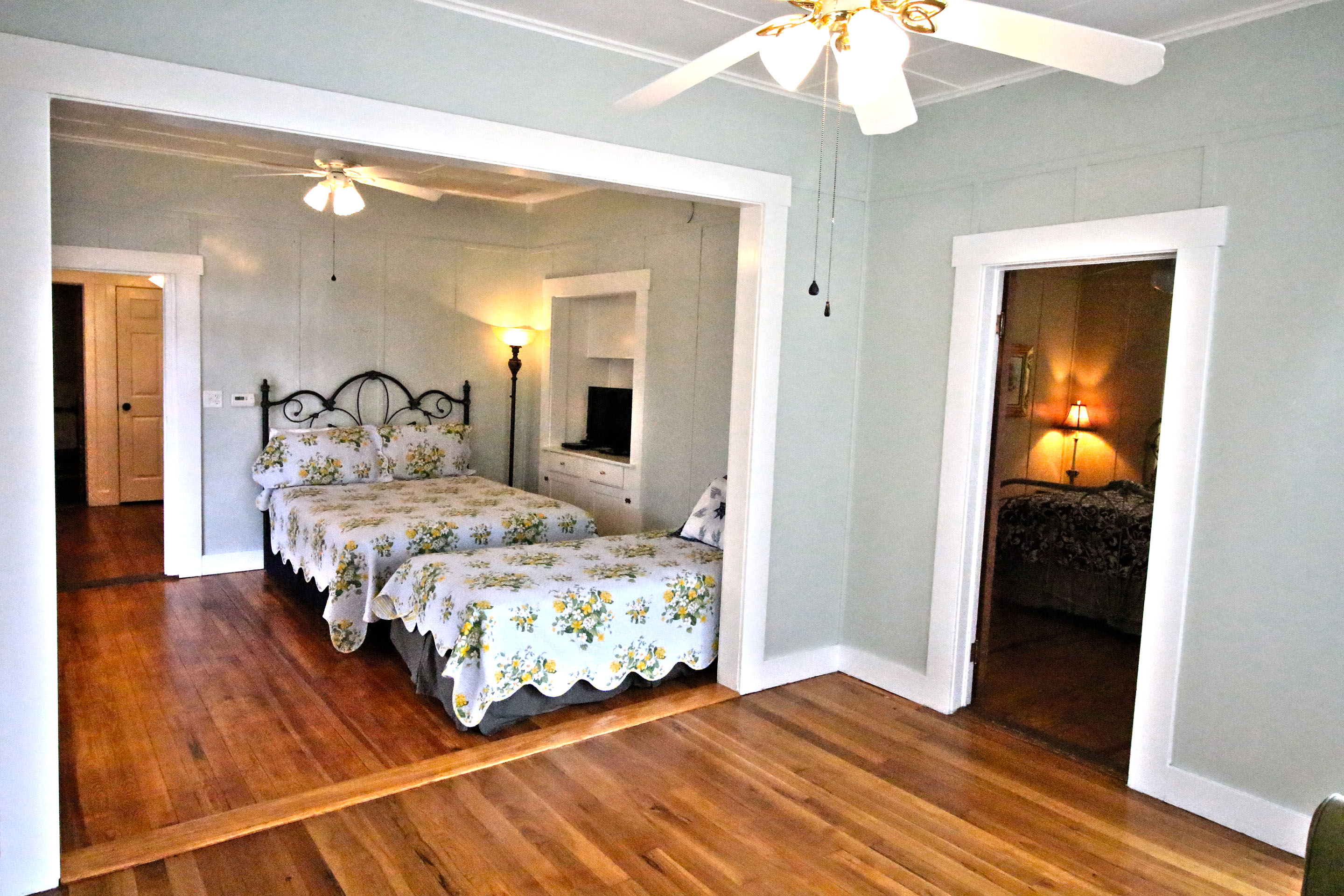 A wide view of a room with two beds and a doorway to another room